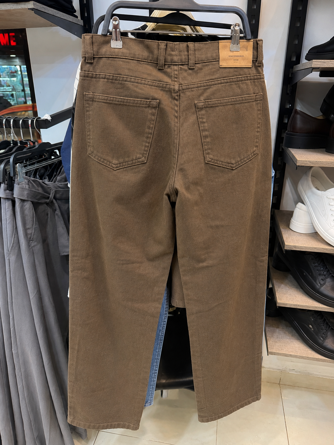 Rare brown washed jeans with a relaxed fit and faded denim texture, displayed on a hanger.